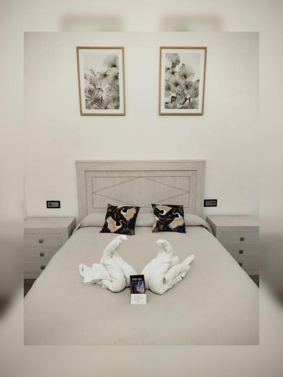a bedroom with a bed with two white hands laying on it at Apartamento Martina 1 in Mérida