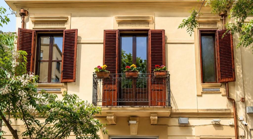a building with three windows with flowers on a balcony at Le case di Rebecca in Palermo