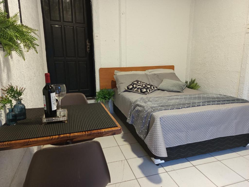 a bedroom with a bed and a table with a bottle of wine at Suíte aconchego in Domingos Martins