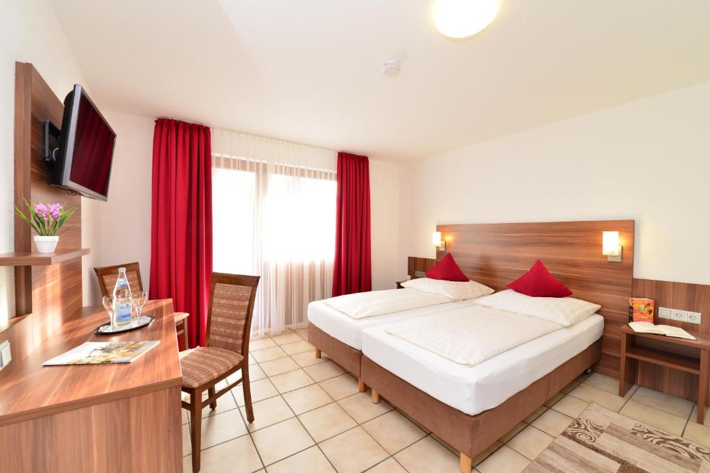 エスリンゲンにあるホテル アム ブッフバルトのベッドとデスクが備わるホテルルームです。