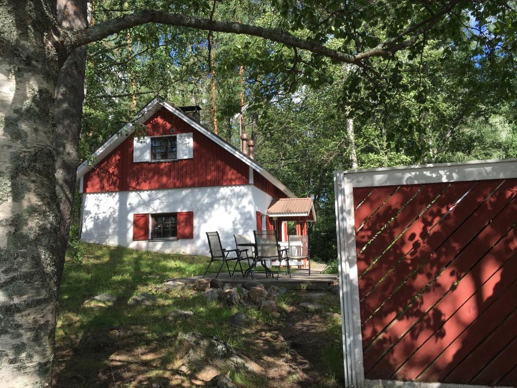 um celeiro vermelho e branco com uma mesa e cadeiras em Linkkumylly Cottages em Mäntyharju