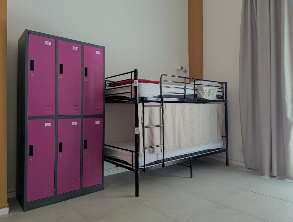 a room with two bunk beds and pink lockers at inScialla Hostel in Trapani