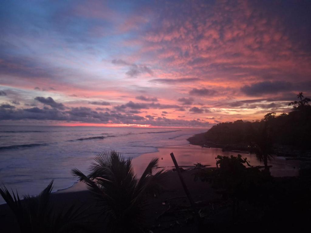 a sunset on a beach with the ocean at Origen ZelvaMar BahiaSolano in Bahía Solano