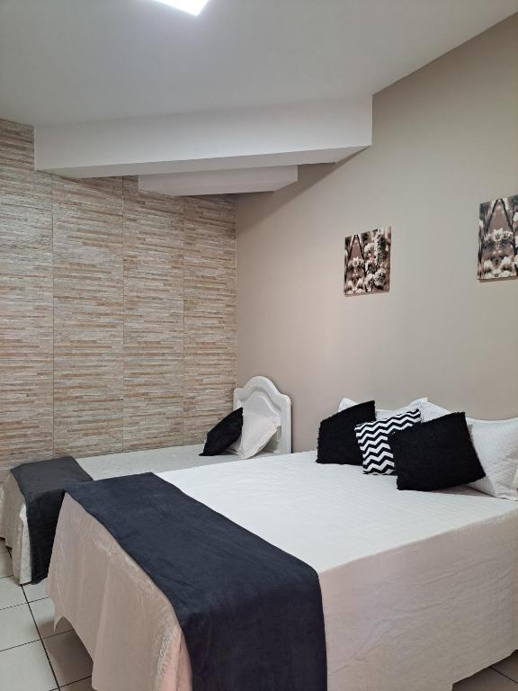 a bedroom with two large beds with black and white pillows at Quarto confortável em Diamantina in Diamantina