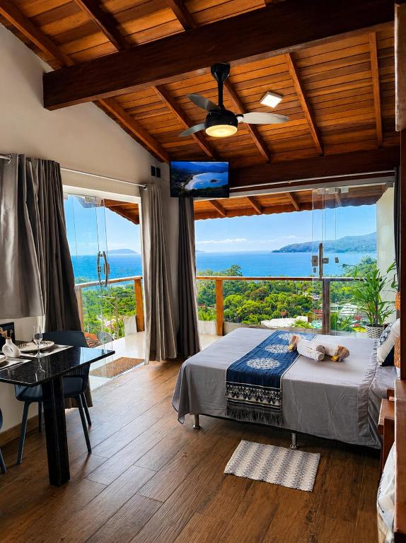 a bedroom with a bed and a view of the ocean at Studio Shogun Vista, Ar, Vaga 5 min do mar in Ilhabela
