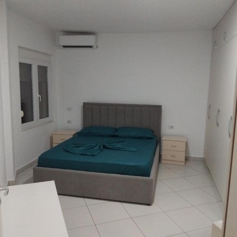 a bedroom with a bed with a green blanket at Private Rooms in Velipojë