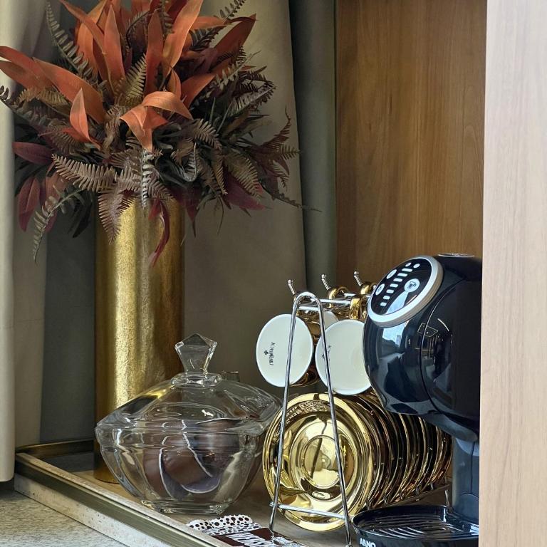 ein Tisch mit einer goldenen Vase, in der eine Pflanze steht in der Unterkunft Royale Studio in Criciúma