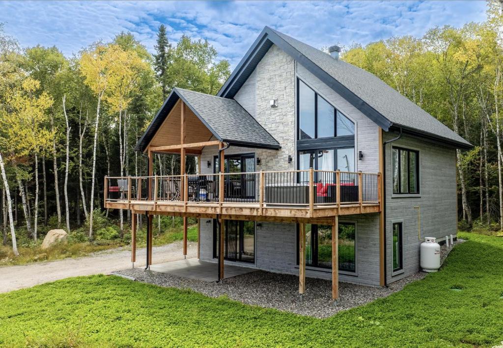 a house with a large deck on the side of it at Käbane Nova - La Chaleureuse in Baie-Saint-Paul