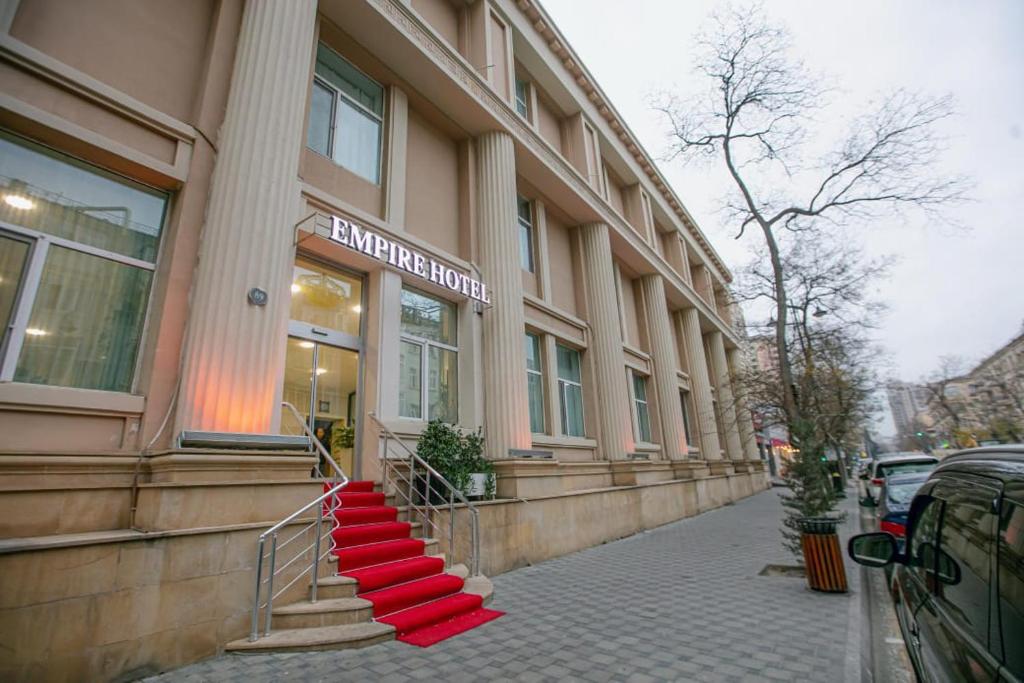 a building with red steps in front of a store at Empire Hotel Baku F1 view in Baku