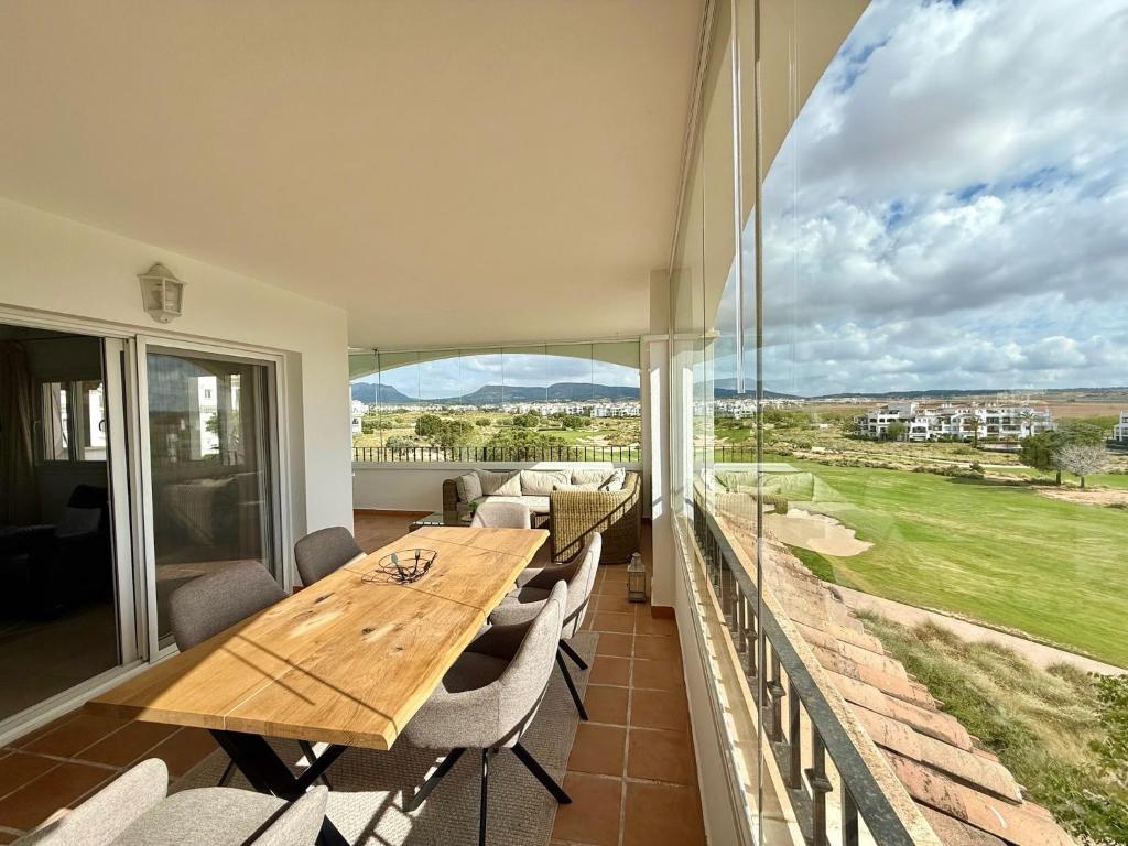 a balcony with a wooden table and chairs and a large window at Beautiful apartment with golf and mountains view in Sucina