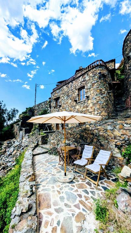 a table and chairs with an umbrella in front of a building at Cantinho do Talasnal in Talasnal