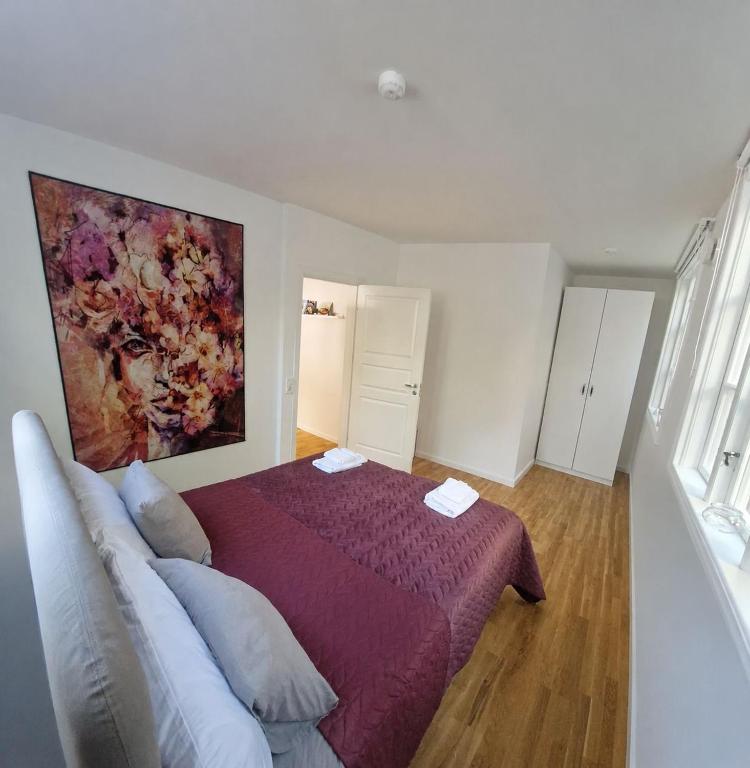 a bedroom with a purple bed and a painting on the wall at Central City Apartment B in Nyköping