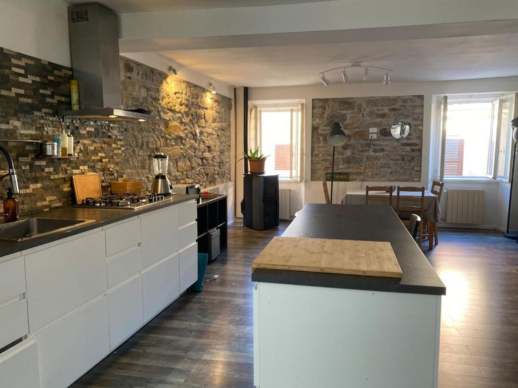 a kitchen with white cabinets and a stone wall at Casa Alice in Muggia