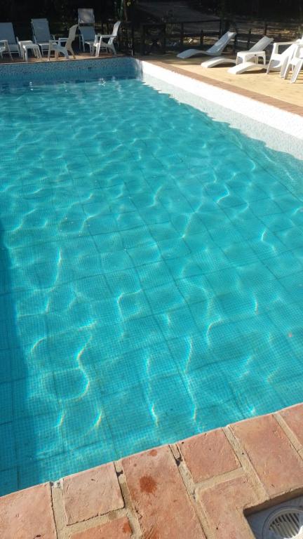 a large blue swimming pool with chairs in it at Cabañas del bosque in Merlo