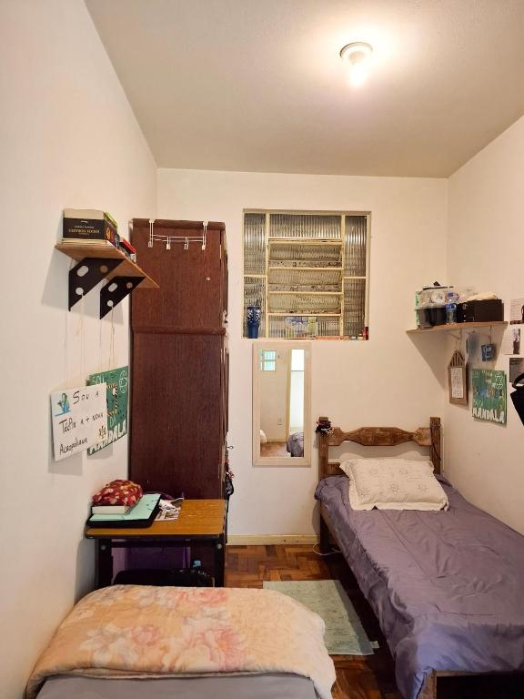 a bedroom with two beds and a table and a window at República Mandala - Quarto duplo 2 in Ouro Preto