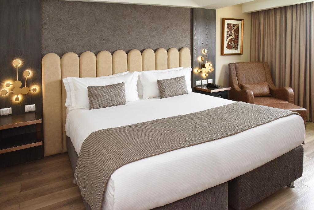 a bedroom with a large white bed and a chair at Hotel HW Libertad in Santiago