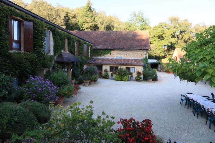 una casa con un patio con bancos y flores en La Ferme Fleurie en La Roque-Gageac