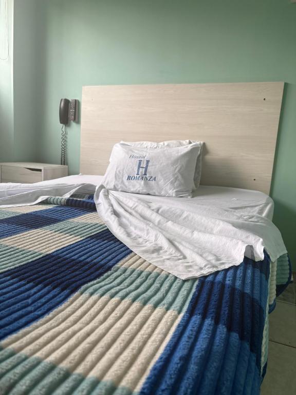 a bed with a white pillow on top of it at Hotel Romanza in Bogotá