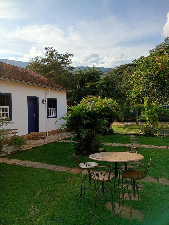 a patio with a table and chairs in a yard at Pousada Arco íris na Serra in Tiradentes