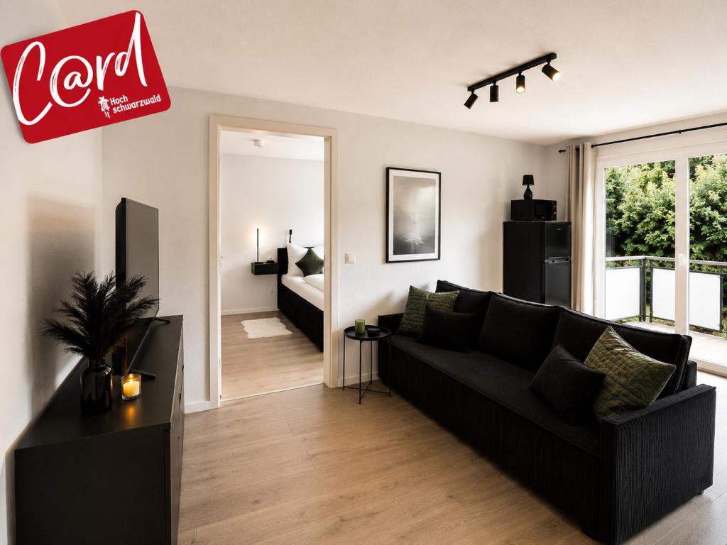 a living room with a black couch in a room at Design Apartment 5 am Titisee mit Kamin, E-Ladestation, Balkon, Top Lage in Titisee-Neustadt
