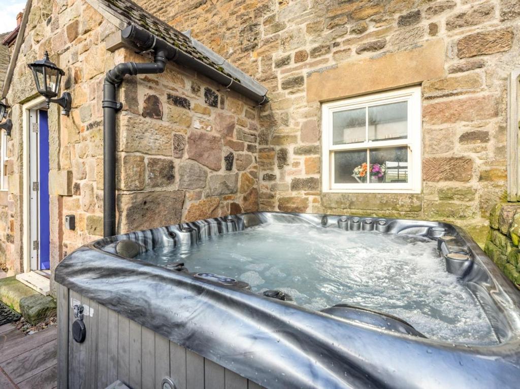 a hot tub in front of a stone building at 2 Bed in Belper oc-74965 in Crich