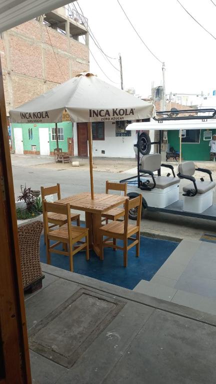 a table and chairs with an umbrella next to a boat at casa posada paracas in Paracas