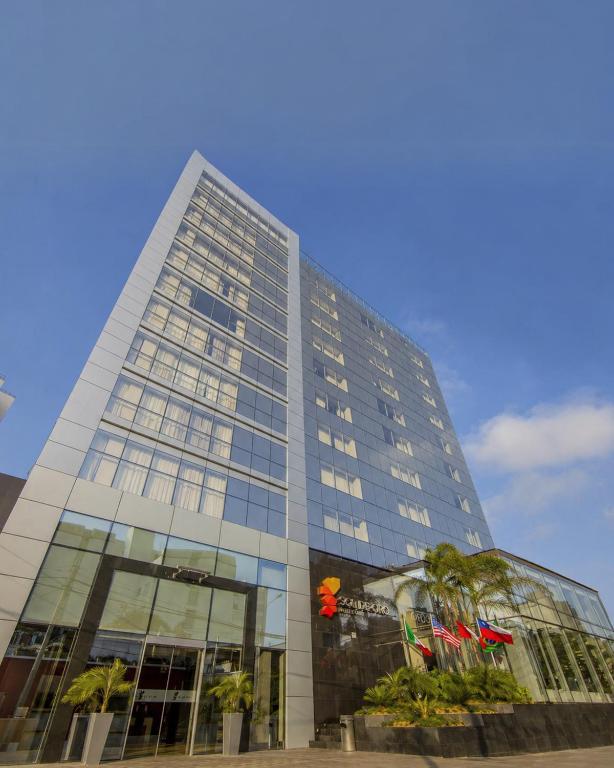 a tall building with a palm tree in front of it at Sol de Oro Hotel & Suites in Lima