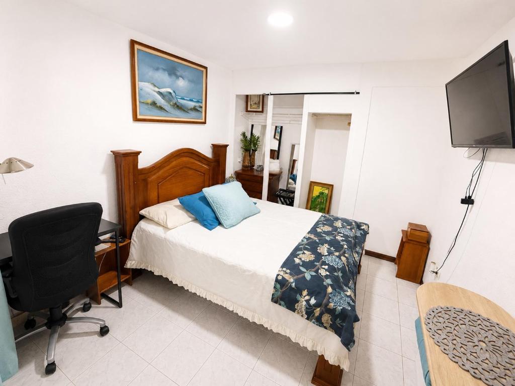 a bedroom with a bed and a desk and a television at Alojamiento Cereza 2 in Alajuela