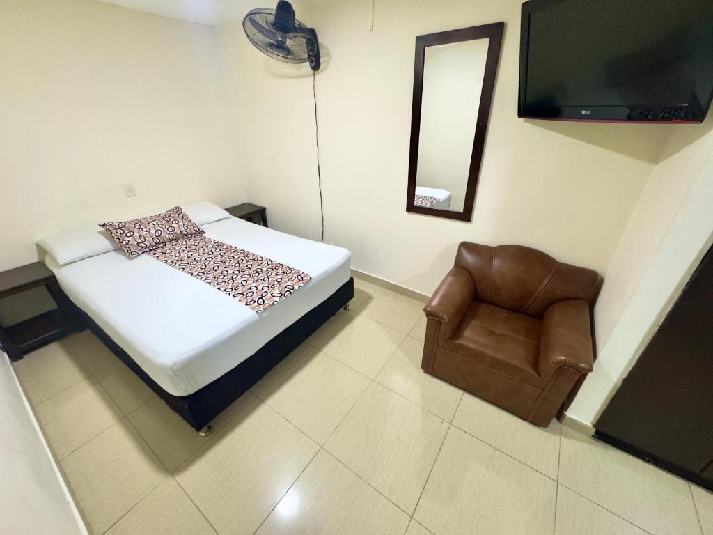 a bedroom with a bed and a chair and a mirror at Hotel Tucan Pereira in Pereira