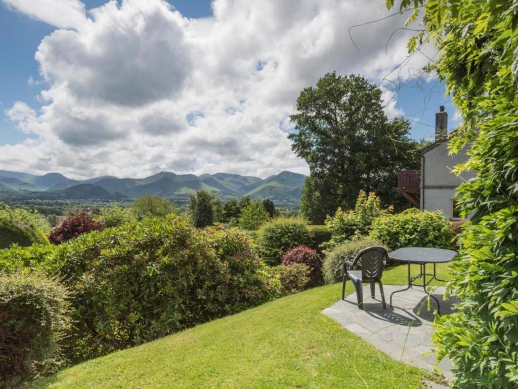 a table and chairs in a garden with mountains in the background at 3 Bed in Keswick oc-sz328 in Applethwaite
