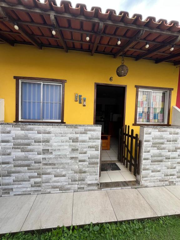 a house with a yellow wall and a door at Casa beira mar Jacaraipe. in Serra