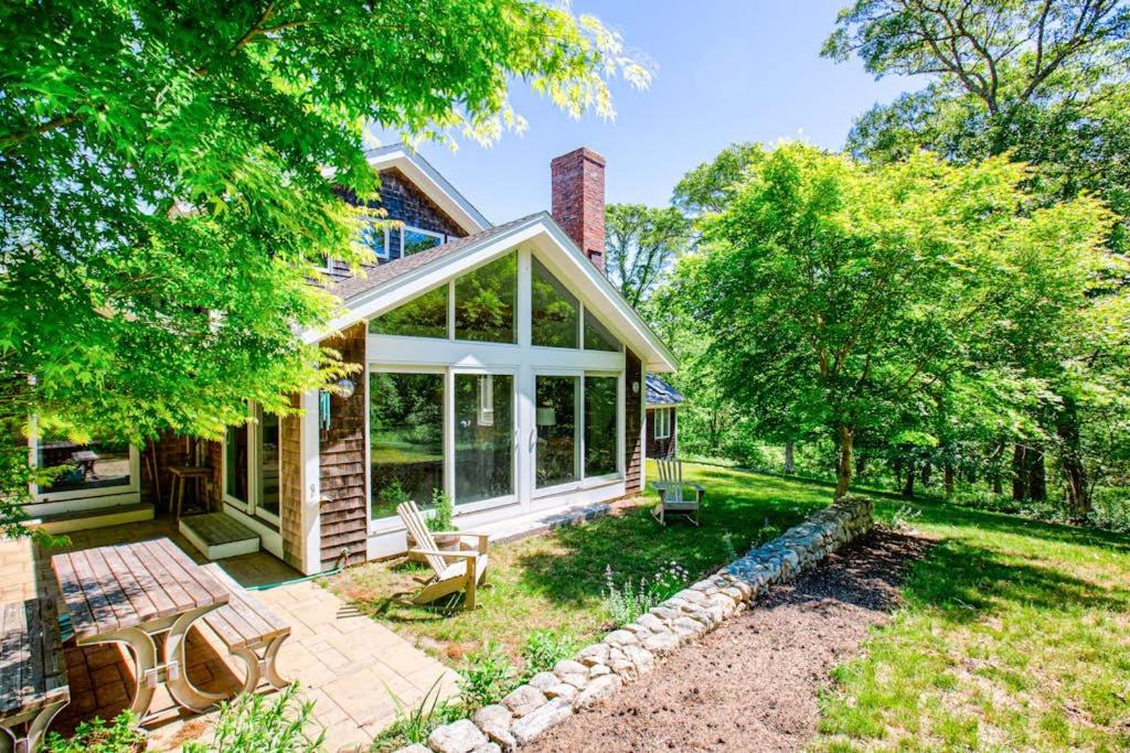 ein Haus mit einem großen Wintergarten und einer Terrasse in der Unterkunft Hillside Oak in Chilmark