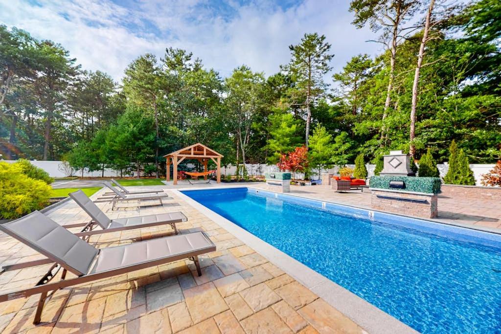 a swimming pool with chairs and a gazebo at Cape Castle in Mashpee