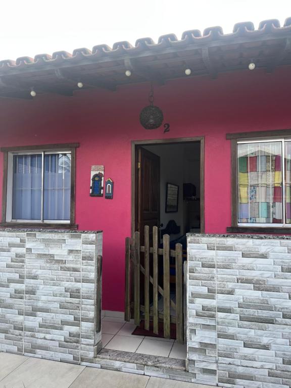 a pink house with a gate and a door at Casa quadra praia Jacaraipe! in Jacaraípe