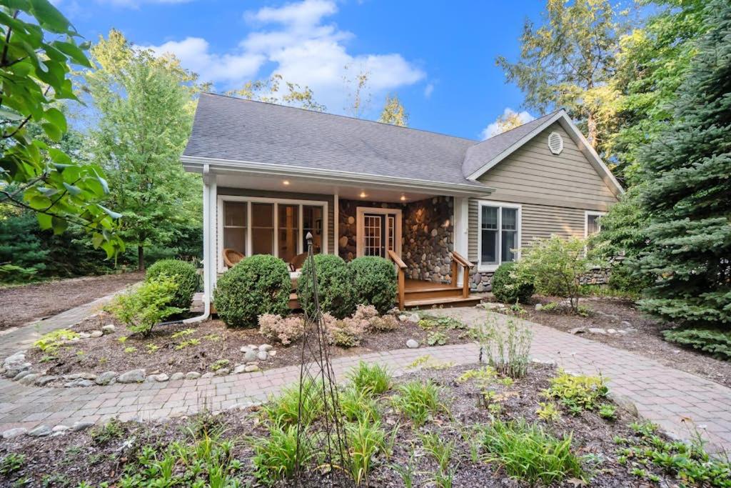 a small house with a porch and bushes at Between the Lakes in Glen Arbor