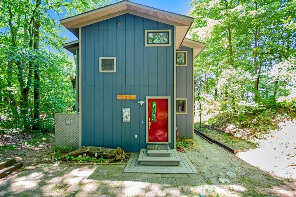 a blue house with a red door in the woods at Jacobia Lakefront Retreat in Covert