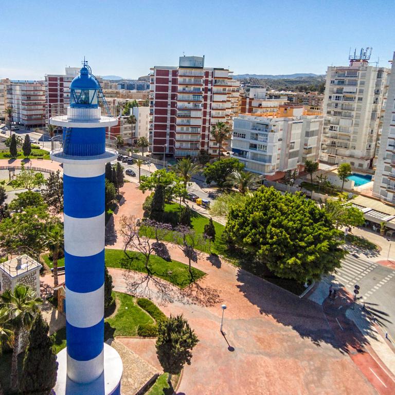 a blue and white lighthouse in front of a city at New Apartment Alejandro in Torre del Mar