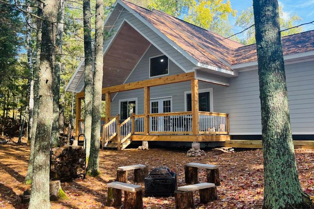 a house with a porch in the woods at Chalet on the Bay in Saint Germain
