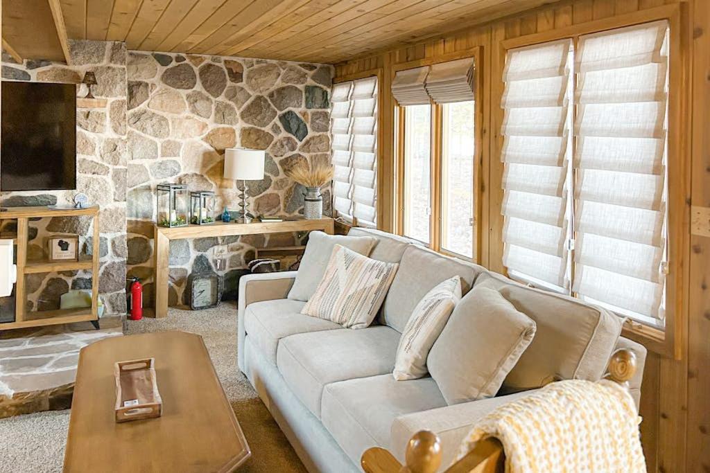 a living room with a couch and a stone wall at Stormy Point Cabin in Conover
