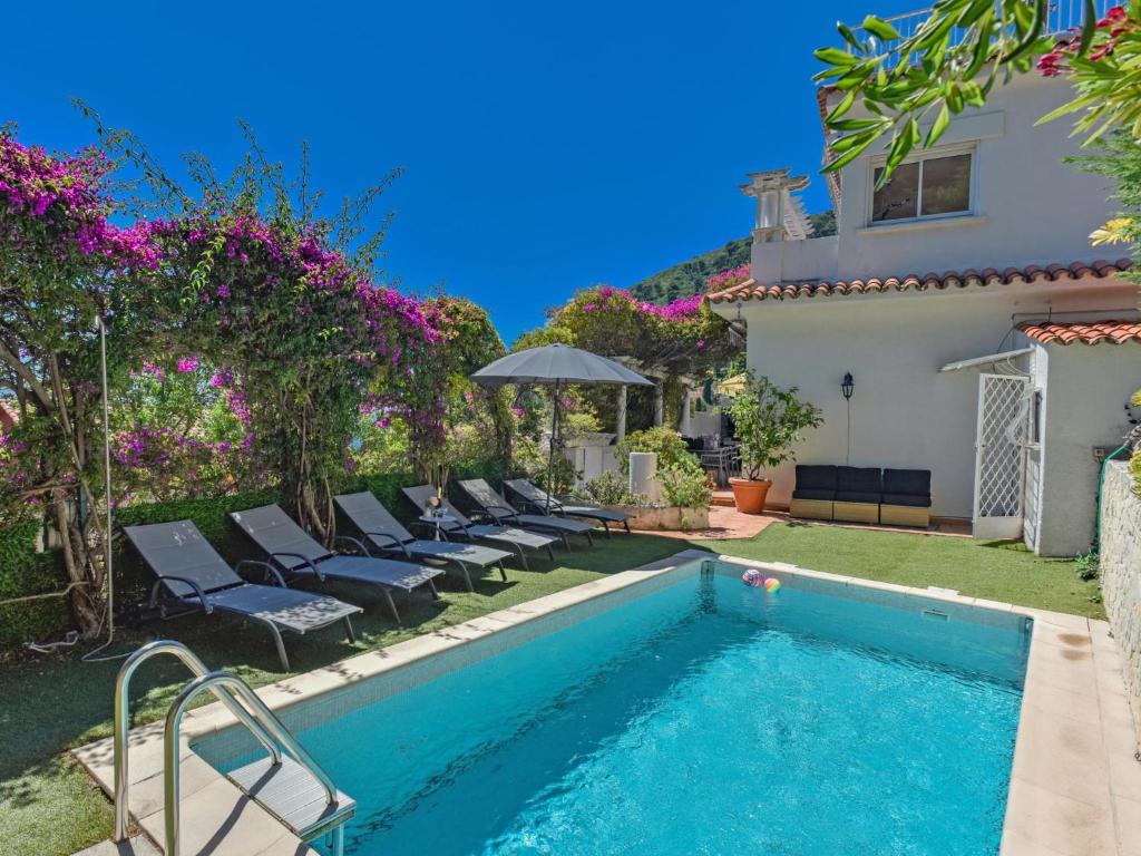 a swimming pool with chairs and a house at Paulette in Éze