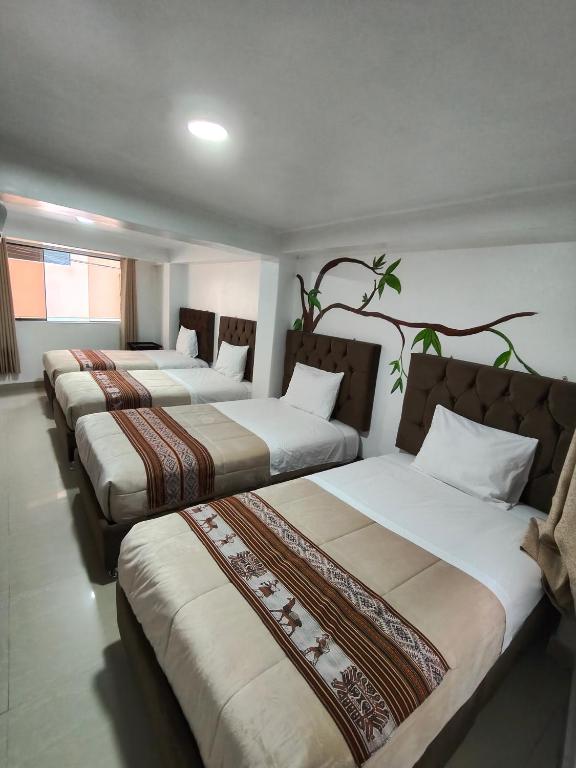 a row of four beds in a room at Hostal Ñustas INN in Machu Picchu