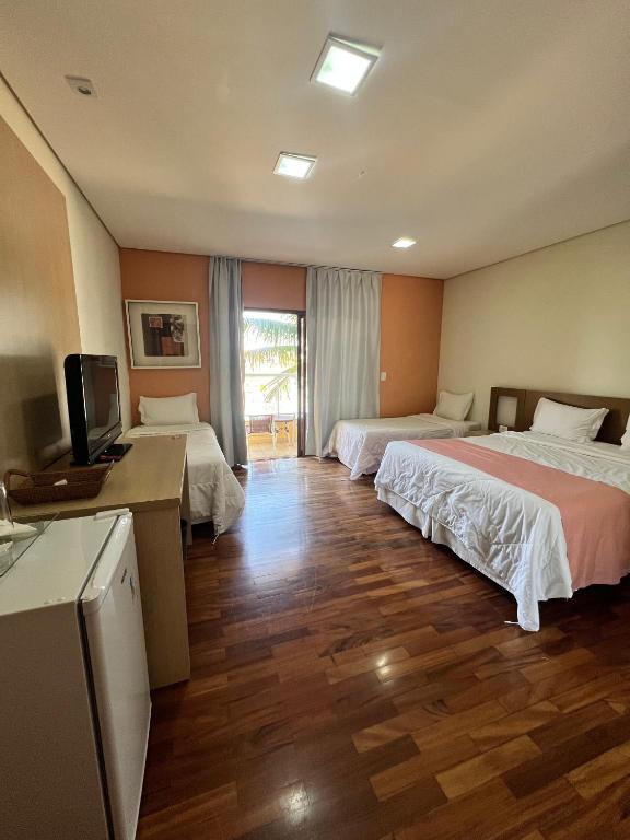 a hotel room with two beds and a television at Ramada by Wyndham Furnaspark in Formiga