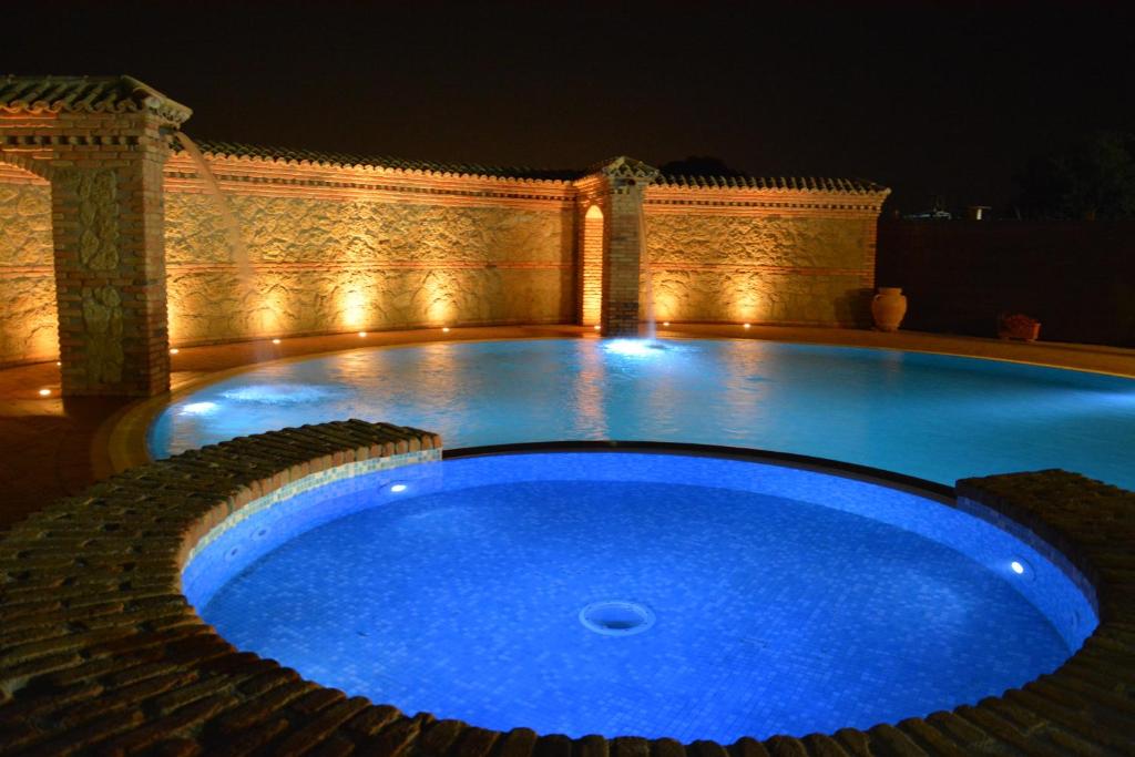 a large blue swimming pool at night with lights at La Piana Dell'erika in Aprilia