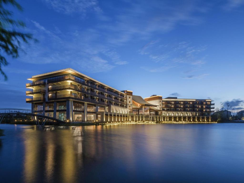 un edificio accanto a uno specchio d'acqua di Pullman Zhouzhuang a Kunshan