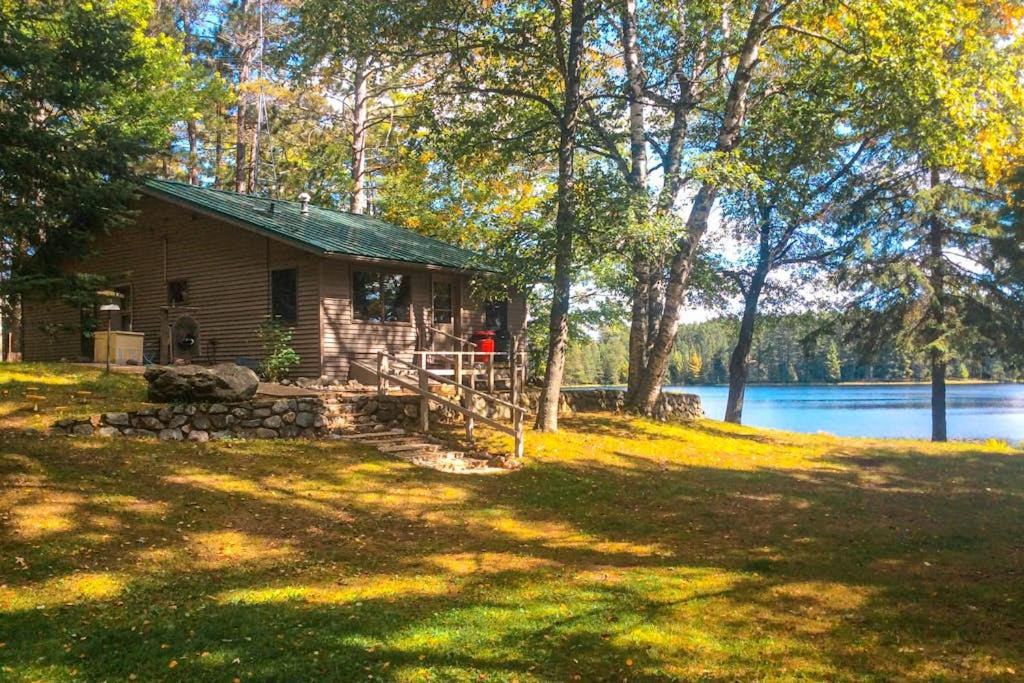 a log cabin in a field next to a lake at Hotter's Cabin in Eagle River