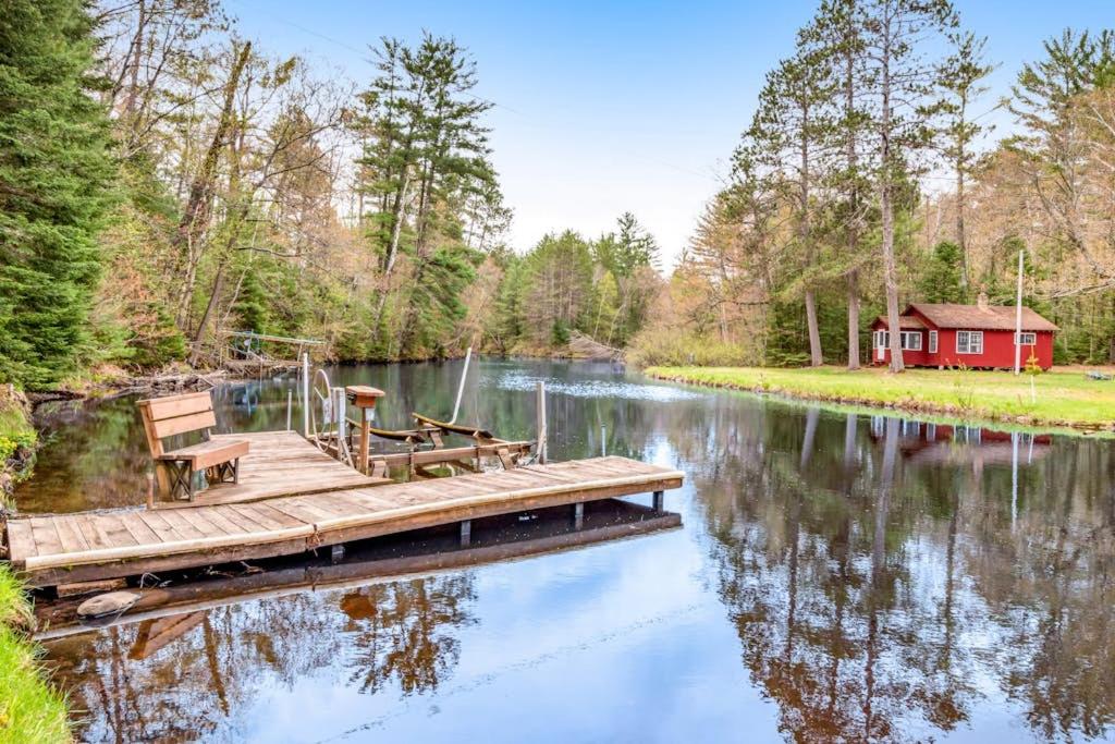 a dock with benches and a red house on a lake at One Acre Wood in Eagle River