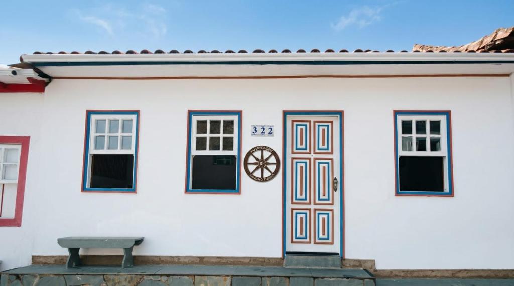 a white house with a door and a bench at Hospedagem Rancho Fundo in Diamantina