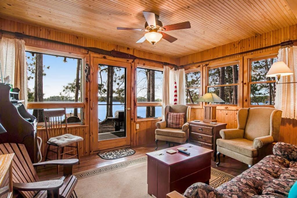 a living room with wooden walls and a ceiling fan at Bucky's PineIsle Retreat in Three Lakes
