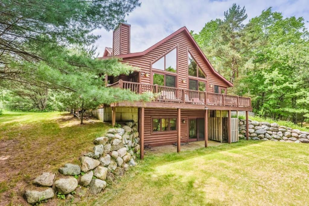 a large wooden house with a stone wall at Northwoods Getaway in Arbor Vitae