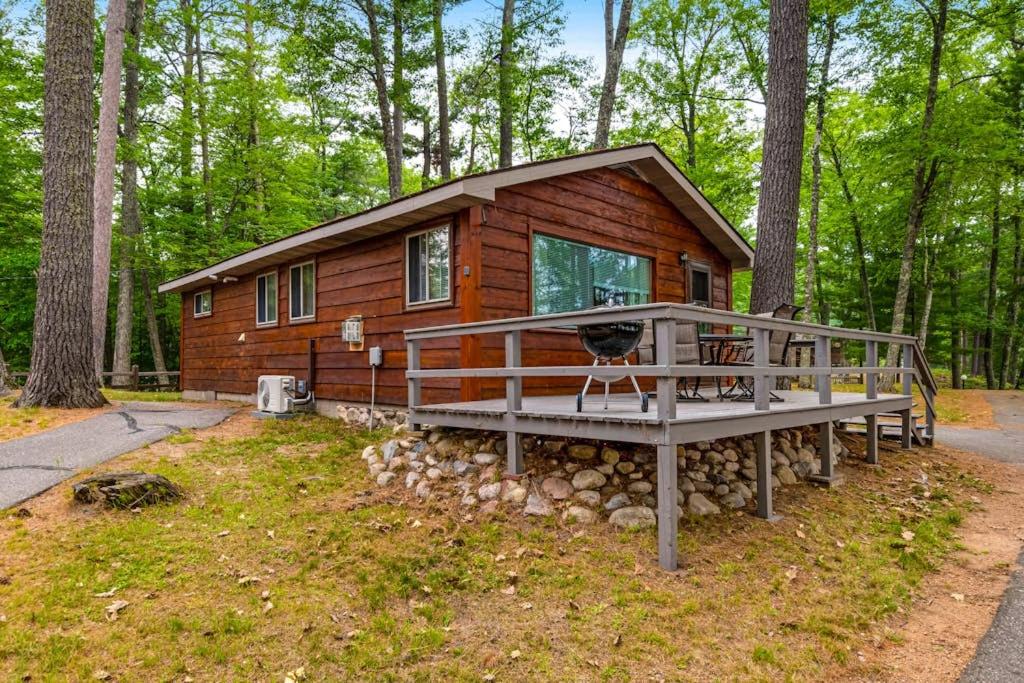 a small log cabin in the woods with a porch at Our Lakeside Legacy in Saint Germain